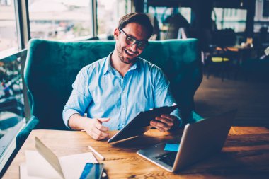 Optik Gözlük ücretsiz internet wifi içinde bağlı modern netbook aygıt ile tahta masada oturan üretken çalışma yüksekliği mali sonuçlarından sevindirici kafede mutlu başarılı sahibi