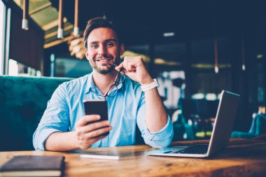 Yarım uzunluk portresi başarılı girişimci modern telefon uzaktan dizüstü bilgisayarda kafeteryada çalışan 4 g bağlı iç internet uygulaması ile ödeme yapma sakallı