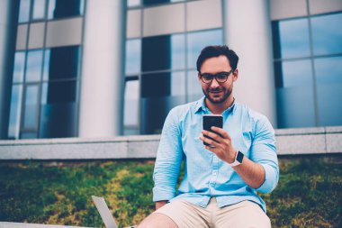 Pozitif sakallı adam Eyewear mesaj ile dijital smartphone aygıt office promosyon arka plan kopya alanı alanının yakınında oturan Internet ikramiye hakkında cep telefonu operatörü tarafından sürpriz