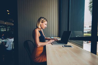 Dalgın işkadını kulaklık modern netbook sahte alanı ile çalışan öğretici çevrimiçi ve dinleme bilgi izliyor. Konsantre kadın grafik tasarımcı doig uzak iş laptop Cafe