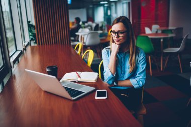 Genç kadın şık Eyewear sağlamak gözleri koruma şık coworking oturan 4 g internet bağlantısı ile ilginç eğitim webinar online modern dizüstü bilgisayarda izlemek için konsantre