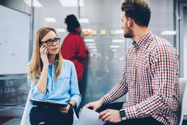 Kadın öğretmen Eyewear vizyon Üniversitesi'nde yetenekli öğrenci ile özel ders yürütürken Smartphone'da işleci ile konuşmak için. Öğretmen modern telefon molası sırasında iletişim