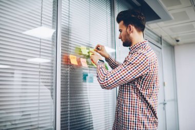 Sopa verimli öğrenme ayakta şık coworking uzayda için yazılı yabancı sözcükler kullanarak yetenekli rahat giyinmiş öğrenci. Genç erkek öğretmen tutkal renkli kağıtlar üniversitede ders hazırlama