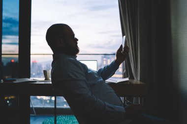 Smartphone uzak yapma konusunda yetenekli erkek freelancer okuma yayın çalışması evinde akşam, konsantre adam bildirim bankacılık uygulaması üzerinde online para kazanmak telefon üzerinden kontrol