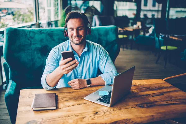 Smilende Mannlig Designer Høretelefoner Som Leser Melding Digital Telefon Datamaskinen – stockfoto