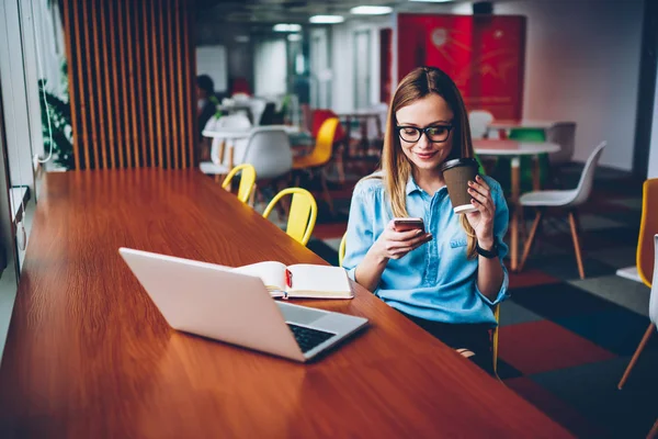 开朗时尚的女性博客更新自己的网站 以检查邮件在智能手机上享受美味的咖啡外卖坐在笔记本电脑在 Coworking 时髦学生阅读短信与好消息 — 图库照片