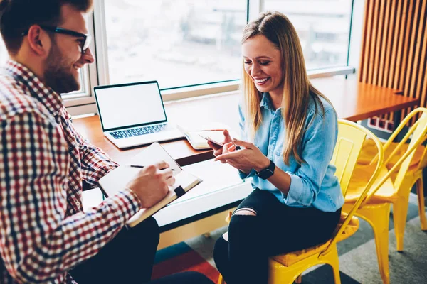 Neşeli erkek gazeteci bilgileri Not Defteri'nde şık coworking alan pozitif kadın Tasarımcısı ile görüşme sırasında yazma. Başarılı öğrenciler ekip çalışması organizasyonu planı tartışıyor