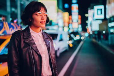 Şık giyimli hippi kız Eyewear gece şehir ışık yansıması ile güzel aydınlatma hayran ile. Muhteşem erkek deri ceket akşam kentsel arka plan üzerinde dururken merak içinde