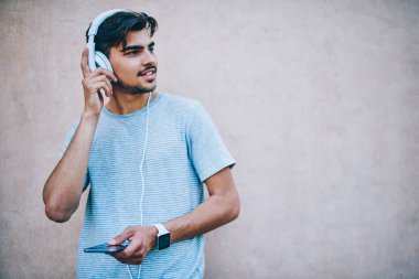 Pozitif hipster adam sevgilisi müzik çalma listesindeki Kulaklık dinleme elektronik şarkıları kopyalama alanı alanı ile promosyon arka plan üzerinde smartphone aygıt duran bağlıyken uzak arıyorsunuz