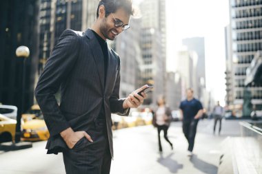 Neşeli erkek tüccar Smartphone cep telefonu ile internet sitesinde iyi iş haberleri okurken gülmekten şık takım elbise giymiş. Mutlu Yöneticisi alınan bildirim cep üzerinde yüksek mali dengesinin