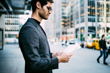 İcra Müdürü iş yayın okuma kağıt belgeleri ile yeni York.Confident sokakta Manhattan mali infromation kontrol dalgın başarılı bir tüccar yan görünüm konsantre