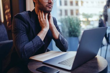 Şık kafede oturan yüksek hızlı internet bağlantısı ile modern dizüstü bilgisayarda formal giyim izlerken online iş sunudaki dalgın genç icra müdürü görüntü kırpılmış