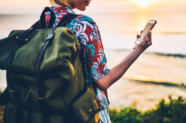 Açık havada eğlence vakit ve dreamland tatil arkadaşlar için video gönderme genç kadın kişi görüntü kırpılmış. Arkadan turist ile okyanus yanında sırt çantası durduğunu batımında görünüşü