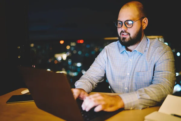在家中工作加班的商人膝上型计算机键盘的研究 熟练的男性博客作者与网络打字的追随者交流在深夜的上网本上的反馈 — 图库照片