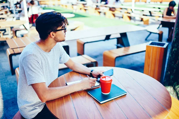 Ponderando Estudante Qualificado Óculos Olhando Para Longe Segurando Smartphone Mão — Fotografia de Stock