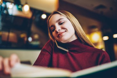 Muhteşem olumlu yetenekli kız öğrenci smartphone telefon sohbet sırasında dinlenme zevk kırmızı kazak giymiş. Şirin mutlu hippi kız ilginç kitap okumak ve Evet