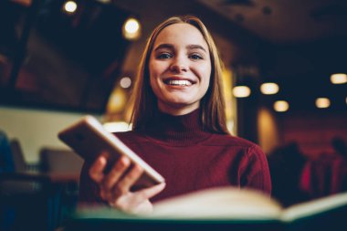 Yarım uzunluk portre rekreasyon rahat kafe içinde modern cihaz ile zevk çekici neşeli kadın Blogger. İçtenlikle kameraya bakarken gülüyor sevimli duygusal hippi kız