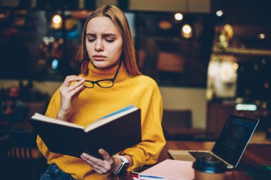 Daha iyi görüş için serin gözlük yaklaşan sınavlar için kapalı hazırlarken büyüleyici yetenekli üzgün kadın öğrenci. Kahve dükkanı literatürde okuma şirin hayal kırıklığına hippi kız