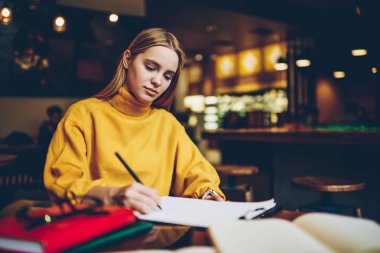 Dikkatle yaklaşan kurs proje için hazırlanıyor ve yaratıcı fikirler kayıt genç çekici akıllı kız öğrenci. Not defteri kapalı oturma için bilgileri yazma akıllı hippi kız