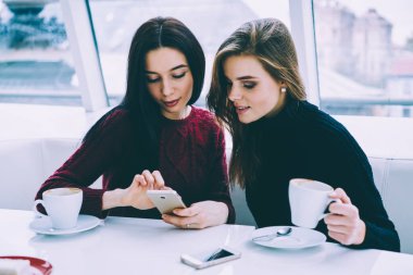 Genç çekici kadın arkadaşlarım smartphone kablosuz internet'e bağlı ilginç video izlerken rahat kıyafet giymiş. Modern teknolojisi çatı kafede oturan kullanarak iş kadınları