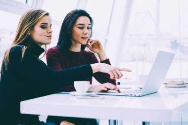 Sevimli sarışın meslektaşım ile birlikte vakit ise dizüstü bilgisayara işaret olumlu yakışıklı sarışın Tasarımcısı. Uzay coworking oturan sırasında modern aygıtta çalışan genç hippi kız