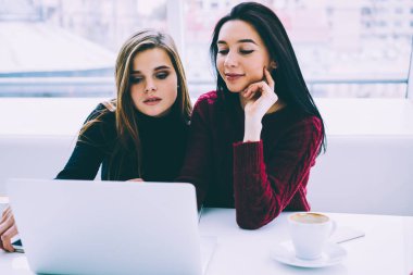 İki iş ortağı kablosuz Internet bağlantısı olan bilgisayarda çevrimiçi sunum izlerken. Hippi kız moda giyim kahve ile yer coworking oturan kendi web sayfası oluşturma