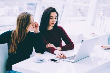 İki iş ortağı kablosuz Internet bağlantısı olan bilgisayarda çevrimiçi sunum izlerken. Hippi kız moda giyim kahve ile yer coworking oturan kendi web sayfası oluşturma