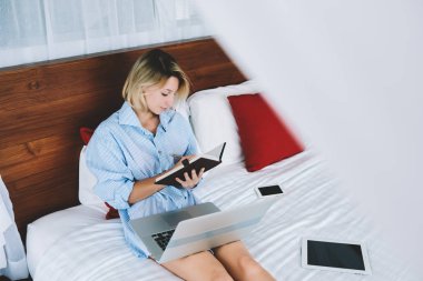Genç kadın tatil otel, kadın serbest meslek seyredebileceğiniz fikirler blog yayın dijital cihazlar ile rahat yatak üzerinde yeniden oluşturmak için seyahat sırasında uzaktan çalışma Not defteri fikirler yazma