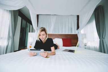 Hippi kız dijital tablet üzerinde rahat yatak gezi sırasında genç kadın sosyal ağlar paylaşım yeni içerik blog evde vakit touchpad üzerinde haber okuma yeniden film izlerken