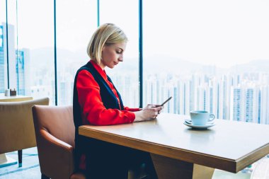Zengin kadın icra müdürü kahve molası kafe, dalgın işadamı Borsası'nda finans haberleri takip cep telefonu kullanarak smartphone dinlenme üzerinde kablosuz bağlantısı üzerinden metin mesajı gönderme