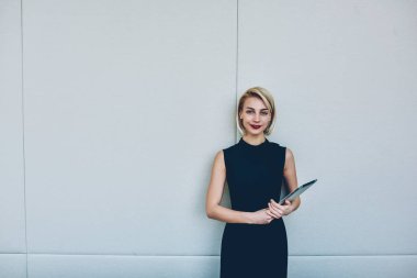 Yarım uzunluk portre investition ile gülümseyen, müreffeh iş zarif siyah elbiseli kadın sahibini memnun promosyon arka plan üzerindeki belgeler ile ayakta muhteşem kadın yatırımcı