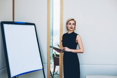 Yarım uzunluk portre sarışın başarılı çalıştırıcı business School'a, sunu touchpad tutan flipchart yakınındaki müreffeh icra müdürü liderlik kursu sunum yapma