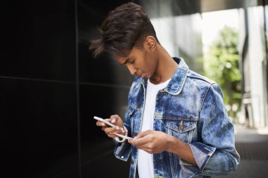 Dalgın hindu genç yazarak kısa mesaj sesleri smartphone ayakta sokakta adam. Aranan telefon numarası elinde tutan kartvizit hangi telefondan üzerinde kot ceket hipster adam giymiş