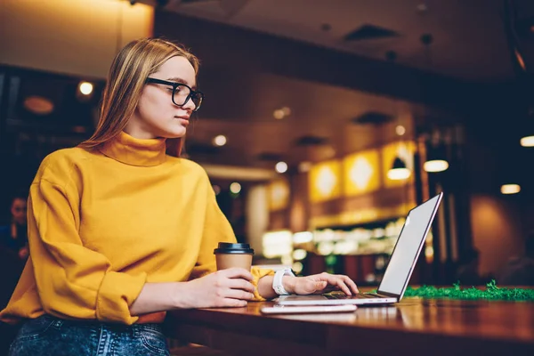 漂亮的创意女性文案在时尚眼镜坐在咖啡馆和搜索信息的笔记本电脑空白复制空间屏幕为您的广告信息内容 — 图库照片