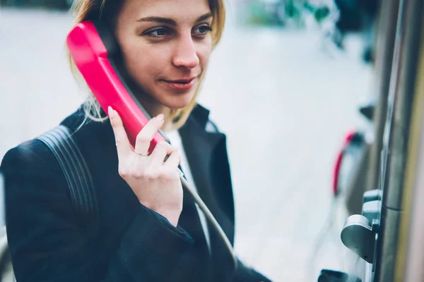 公衆コイン国際接続に満足するいると運営上の会話通り 女性の観光客に文房具電話呼び出しの携帯電話を保持している肯定的な金髪女性 — ストック写真