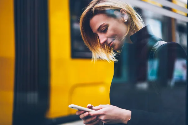 若い女性は 女性旅行者のトラフィックの方法と街のスマート フォンで閲覧のウェブサイト上のテーブル チェックを笑顔輸送バスを待って電話でバンキング アプリケーション経由での支払い — ストック写真