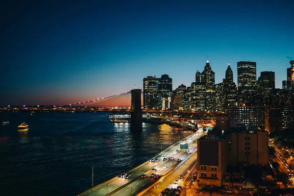 都市金融区的夜视与现代建筑学在河附近 纽约城市景观与被开发的基础设施与摩天大楼桥梁和繁忙的交通在市中心高速公路 — 图库照片
