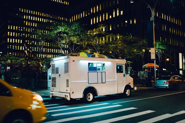 White food truck parked on city street near buildings using for retail business startup, Van automobile with mock up copy space area for brand name selling ice cream parked in urban setting at night