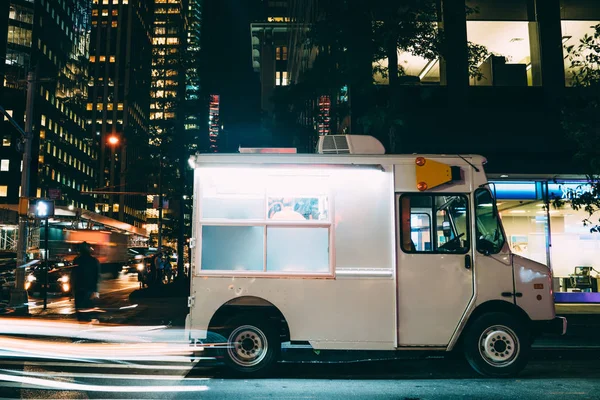 Van automobile with ice cream retail parked on street near building in downtown at evening, business startup with trading sweets via vehicle truck traveling in city distributing food during weekends