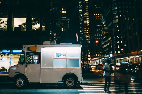 White food truck parked on city street near buildings using for retail business startup, Van automobile with mock up copy space area for brand name selling ice cream parked in urban setting at night