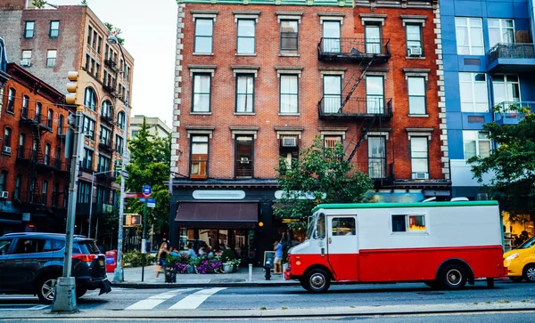 Vintage building exterior in residential district and truck of delivery service driving on road for relocation; traffic on avenue near old architecture with stores and flats in megapolis