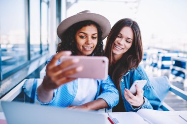 Modaya uygun kıyafet birlikte fotoğraf paylaşımı için 4 g bağlantısı kullanma sosyal ağlarda yapma eğlence keyfini en iyi arkadaşlar selfie cep telefonu kamera için poz kızlarda çok ırklı hipster gülümseyen