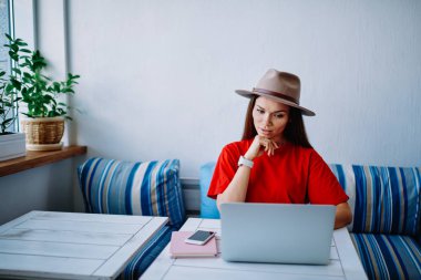 Genç erkek ile dizüstü bilgisayar arama moda giysilerle web mağazası da ağlar Son Haberler okuma ve bilgi kafe iç dinlenme analiz hippi kız alışveriş online yapma trendy şapkalı