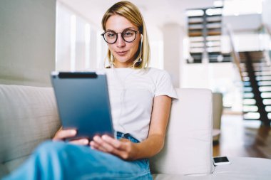 Eyegasses kulaklık dijital Tablet ilginç film izlerken içinde şirin başarılı kadın blogger rekreasyon vaktinizi evinde rahat kanepe üzerinde kablosuz ev internet bağlı