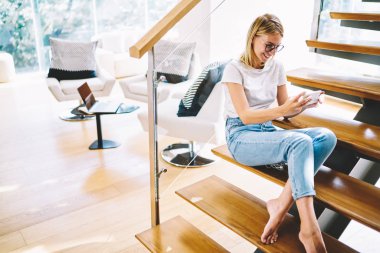 Büyüleyici neşeli kadın bizzat serin gözlük ile sokulgan yolu ile uygulama Smartphone cep telefonu ile video arama sırasında eğleniyor. Web sitesinde cep video izlerken gülüyor sevimli hippi kız