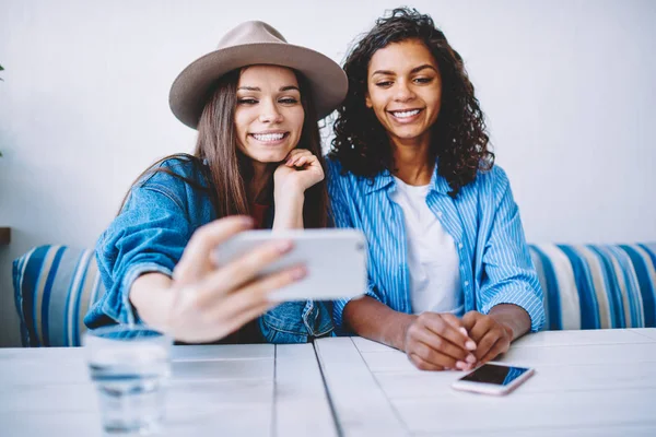 Kafede birlikte vakit smartphone kamera selfie yapmak için poz neşeli en iyi arkadaşlar, modaya uygun kıyafet alma mutlu hippi kız fotoğraf yolu ile hareket eden sosyal ağlar yüklemek için