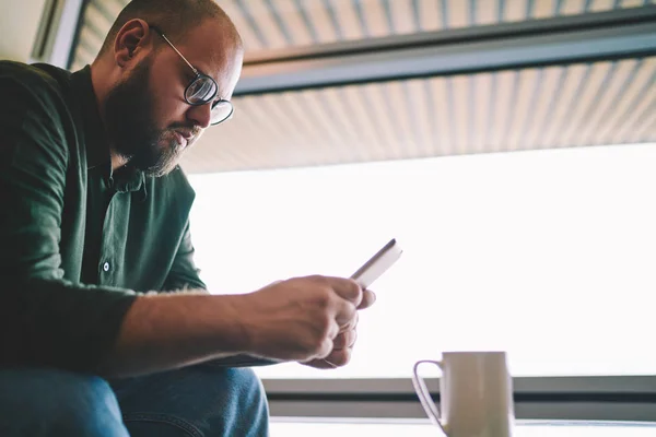 Pensiv Ung Mann Øyeklær Som Ser Mobilapp Smarttelefon Trådløs Internettilkobling – stockfoto