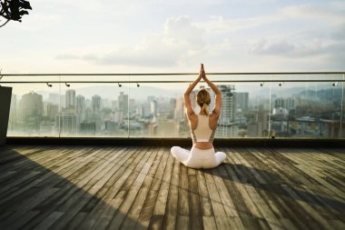Kadın eşofman meditasyon içinde gökdelen Teras duygu huzur içinde megalopolis, açık eğitim sırasında kız tutma zinde ve sağlıklı vücut rahatlatıcı çatı katında yoga pratik poz sırasında ince