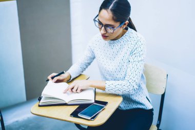 Bilgi Üniversitesi sınıf, zeki genç kadın listesindeki görevleri ödev yerine getirmeye boş sayfaları ile Not Defteri'nde yazma ciddi kız öğrencinin üniversite sınavı testi tamamladıktan konsantre