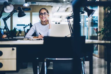 Dizüstü bilgisayar ile çalışma evinde oturan, Office proje planlama yaparken tatil hakkında rüya profesyonel iş kadını gülümseyen verimli iş başarılı kadın yönetici memnun